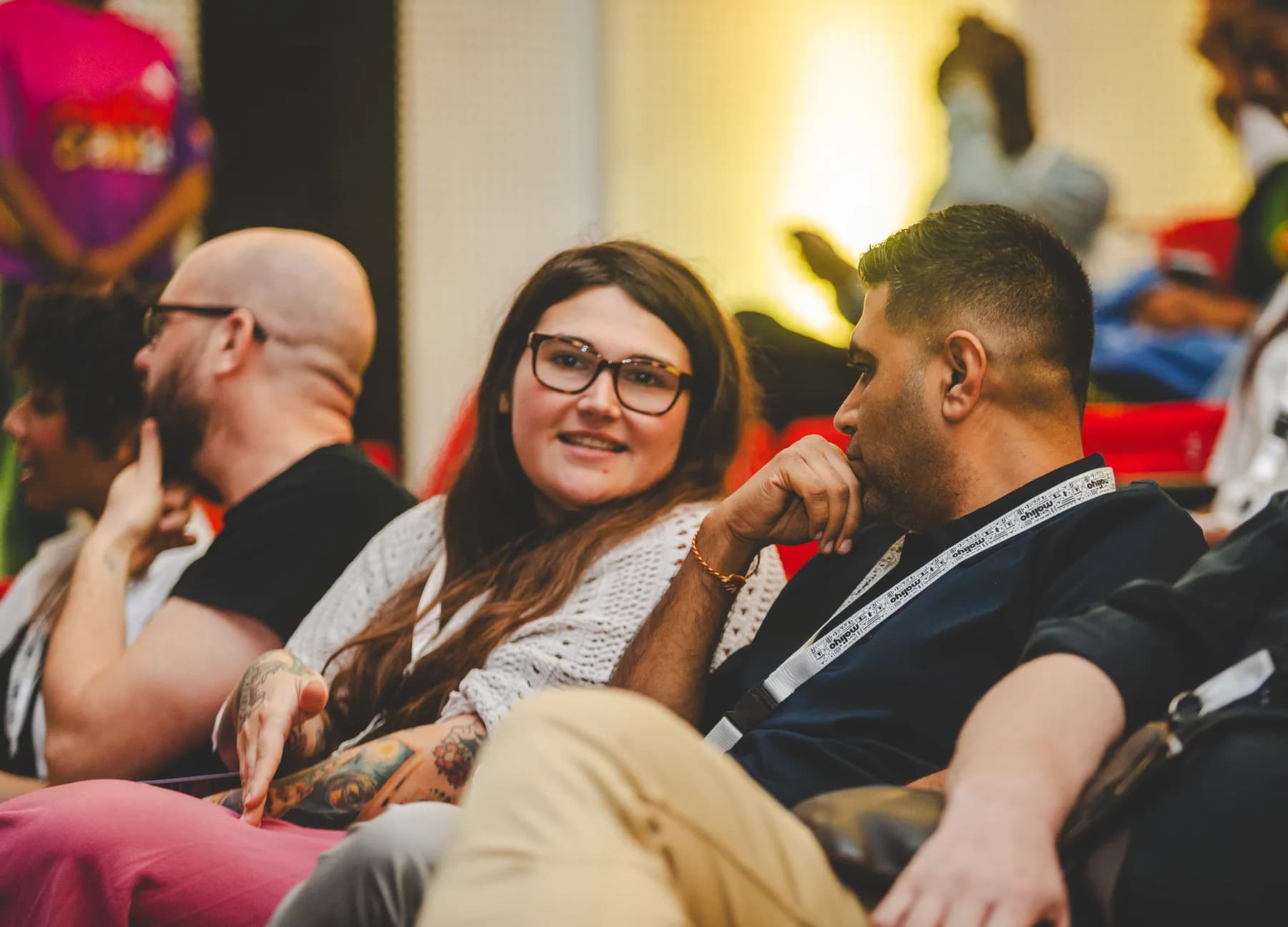 Attendees seated in the audience, a woman in glasses smiling and chatting with the people beside her