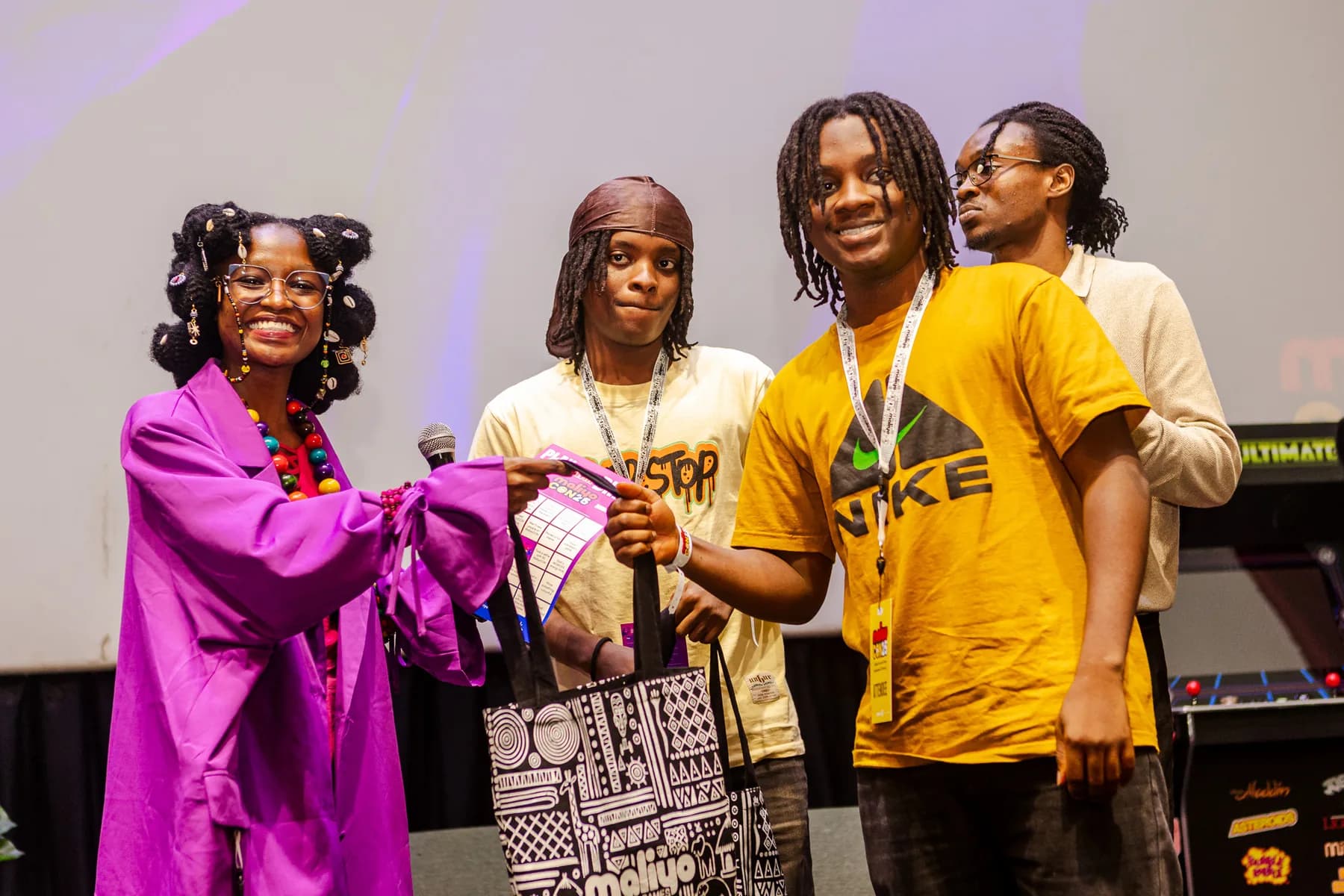 Young winners on stage receiving Maliyo prize bags from a host in a purple outfit